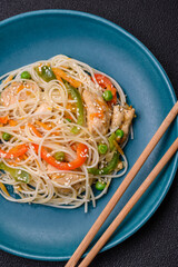 Tasty dish of Asian cuisine with rice noodles, chicken, asparagus, pepper, sesame seeds