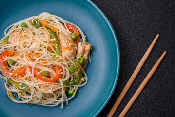 Tasty dish of Asian cuisine with rice noodles, chicken, asparagus, pepper, sesame seeds