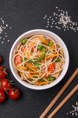 Tasty dish of Asian cuisine with rice noodles, chicken, asparagus, pepper, sesame seeds
