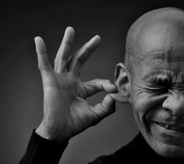 deaf man suffering from deafness and hearing loss on grey black background with people stock image stock photo