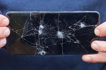 modern new glass broken with cracks black screen of a mobile touch phone in a person's hands on the...