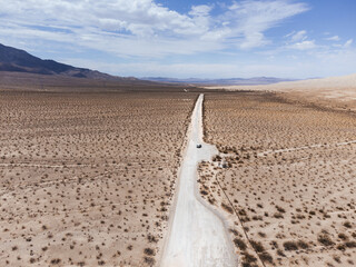 Aerial views of the mojave desert where a dirt road crosses the desert to infinity.