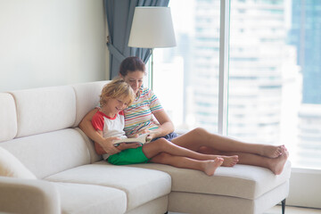 Child and mother read a book in sunny room