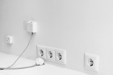 Sockets on a light wall and an electric plug with a wire.