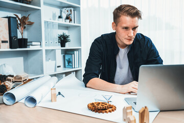 Portrait of architect designer sit at desk in office, brainstorm idea for architectural design project, drafting blueprint with laptop. Professional and modern technology in architecture. Iteration