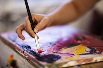 Hand using brush on an artistic painting. Female artist creating art.