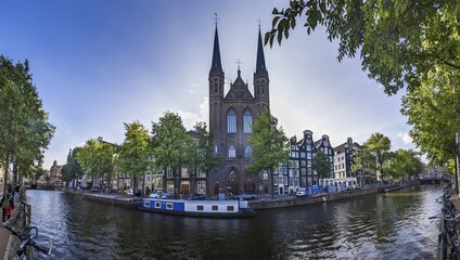 Fototapeta na wymiar Picture of St Francis Xavier Church in Amsterdam with adjacent canal in summer 2023