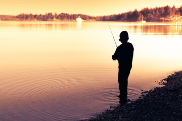 silhouette of a fisherman on a lake at sunset
