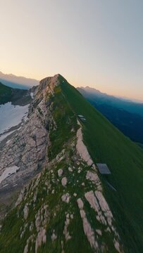 Vertical video. Aerial view mountain ridge gazex industrial tube rock natural texture snow at sunset. FPV sport drone amazing shot picturesque cliff alpine valley sunrise ski resort cable car pillar