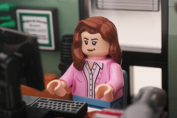 Naklejka premium Tambov, Russian Federation - November 01, 2023 A Lego businesswoman minifigure sitting and working behind a computer in an office. Close up.