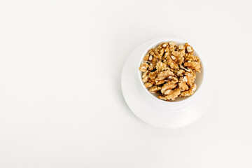 There are peeled walnuts in a white plate.