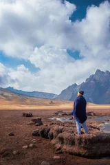 Acrylic prints Alpamayo A lonely Peruvian man with a black cape and scarf standing on dried lake in the Andes mountains looking at the breadth of the landscape