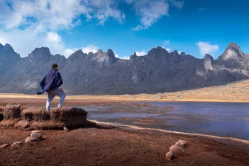 Crédence de cuisine en verre imprimé Alpamayo A lonely Peruvian man with a black cape and scarf standing on dried lake in the Andes mountains looking at the breadth of the landscape