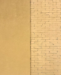 fragment of a building wall with brickwork and a plastered wall painted yellow. Texture or pattern