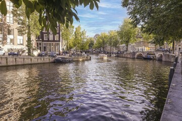 Fototapeta na wymiar View over a typical canal in the Dutch metropolis Amsterdam in summer 2023
