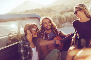 Friends sharing a musical moment during a sunlit road trip