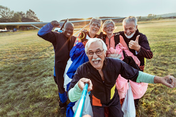 Group of joyful seniors take a selfie after their skydiving adventure