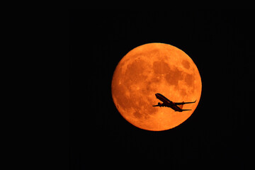 flying plane against the background of the red moon