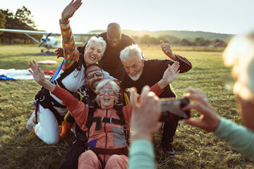 Group of jubilant senior skydivers posing for a memorable photo after landing