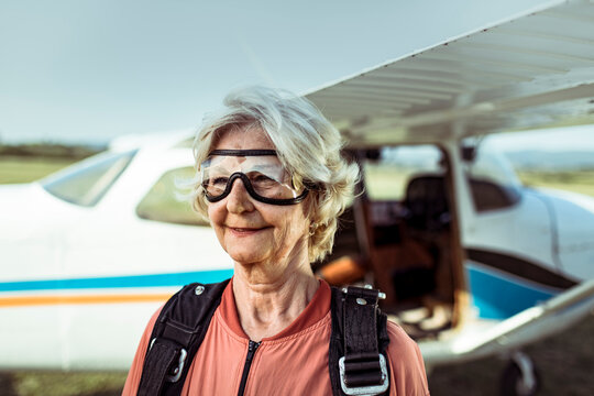 Senior woman geared up for skydiving near an airplane