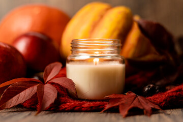 Burning candle on the table next to apples and grape leaves. Autumn Composition