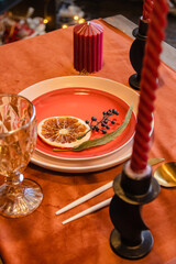 Christmas table setting close-up. In red and orange colors.