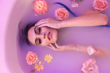 Beauty model in a milk bath with flowers