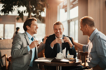 Three businessmen having coffee in a cafe - obrazy, fototapety, plakaty