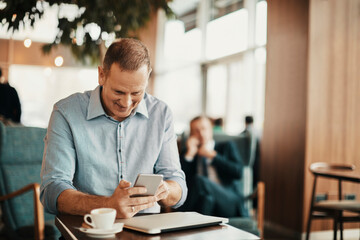 Obraz premium Businessman using a smartphone in a coffee shop