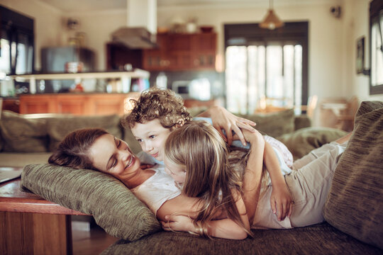 Loving mother embracing her children on the couch