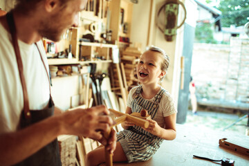 Father and daughter share a joyful moment in a woodworking workshop