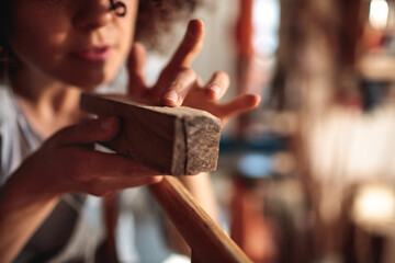 Craftswoman closely examines a piece of wood in her workshop