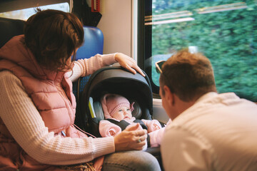 Young happy parents traveling with little baby by train - obrazy, fototapety, plakaty