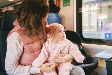 Young happy mother traveling with little baby by train