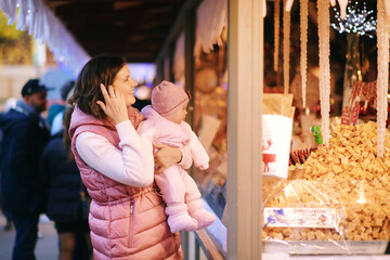 Happy young mother with adorable little baby visiting Christmas market