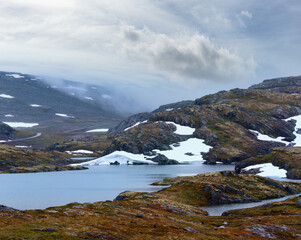 Summer mountain misty landscape with lake and snow (Norway, Aurlandsfjellet).