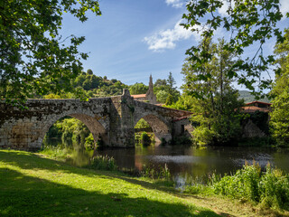 Fototapeta na wymiar Puente antiguo romano de piedra con dos arcos en Allaritz pueblo de Orense provincia de Galicia España en verano de 2021, sobre el río con árboles de hojas verdes.