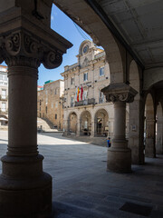 Fototapeta na wymiar Vistas de la plaza porticada del ayuntamiento de Orense desde los arcos con columnas adornadas en un día soleado de verano de 2021, España.