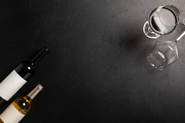 Glasses and bottles with red and white wine on black. Flat lay