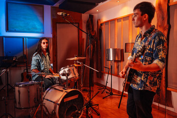 Fototapeta na wymiar Guitar player and drummer experimenting before recording session in music studio.