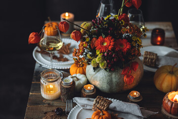 Obraz na płótnie Canvas Fall composition. Orange pumpkins, flowers and candles on wooden table. Family elegant Thanksgiving or halloween dinner. Cozy autumn concept, simple handmade decoration, countryside style, wine