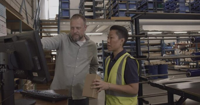 Two Warehouse Employees Looking at Computer