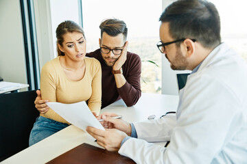 Obraz premium doctor woman man patient hospital care clinic couple young health female medical medicine discussion husband talking wife office family consultation happy appointment treatment