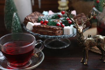 beautiful New Year's Eve candlelit dinner with sweet cakes. Christmas trees and candles in the background