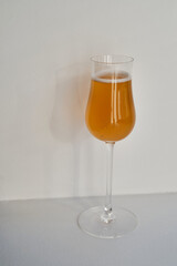 A glass of white wine, a cocktail in the rays of the sun on a light background. Celebrate and enjoy the moment. Tasting of alcoholic drinks. Glass of wine close up