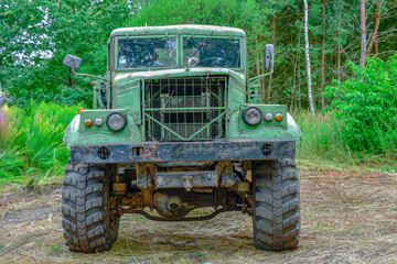 Stara, zdezelowana ciężarówka stojąca w sosnowym lesie. Karoseria kabiny jest koloru zielonego. - obrazy, fototapety, plakaty