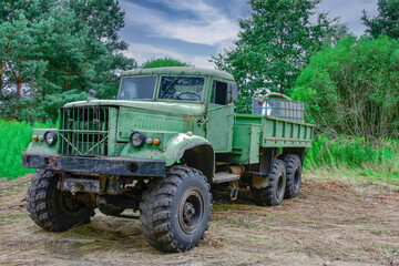 Stara, zdezelowana ciężarówka stojąca w sosnowym lesie. Karoseria kabiny jest koloru zielonego. - obrazy, fototapety, plakaty
