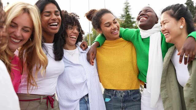 Multi ethnic group of young women hugging outside - Happy girlsfriends having fun laughing out loud on city street - Female community concept with cheerful girls standing together