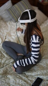 At home, a lovely young woman enjoys her gaming passion with a virtual reality headset.