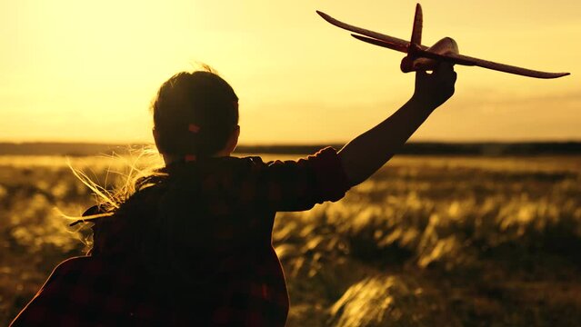 Child play toy airplane. Little girl child wants to become pilot and astronaut. Happy kid runs with toy airplane on field in sunset light. Slow motion. Kid aviator dreams of flying and becoming pilot